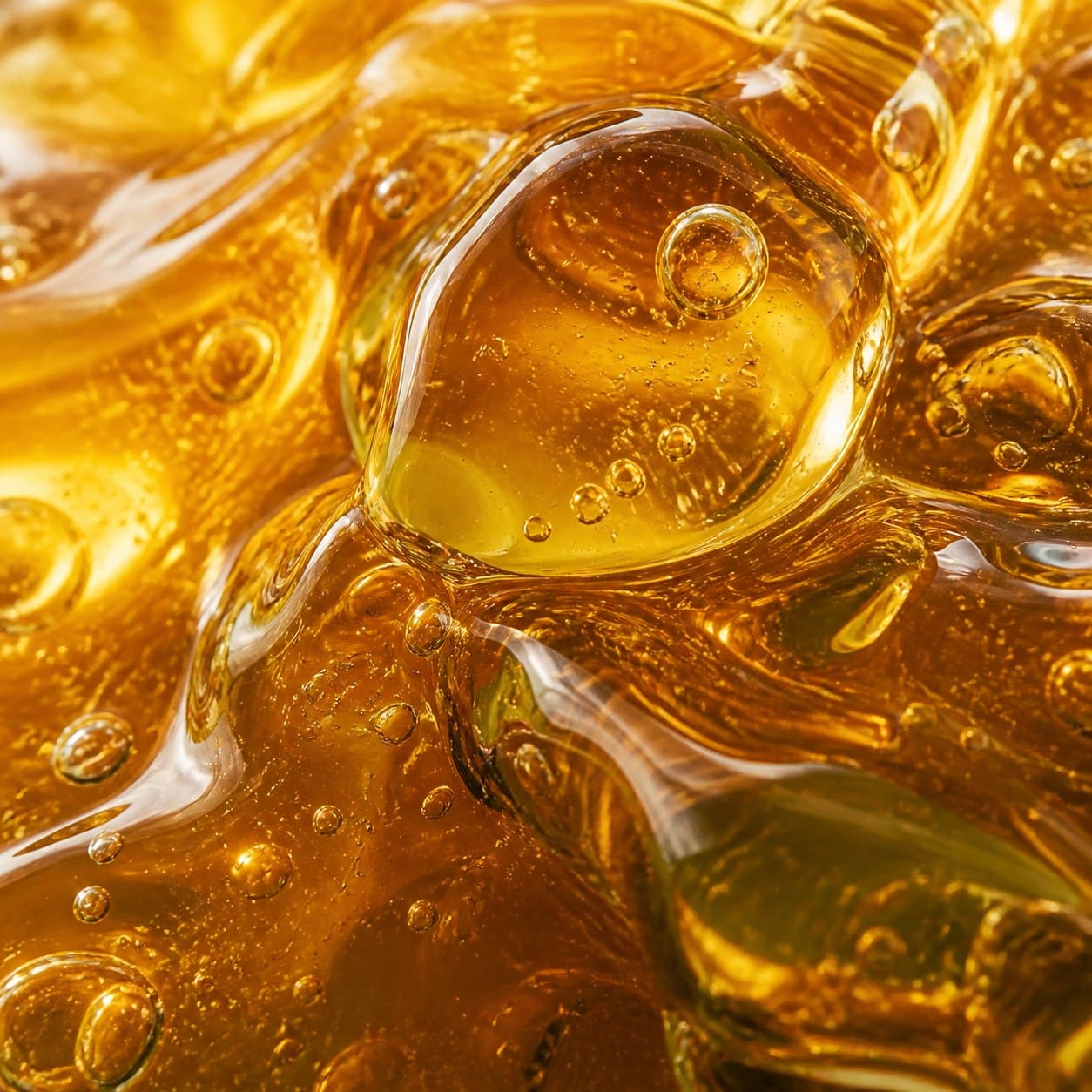 Extreme close-up of luminous golden honey and natural air bubbles